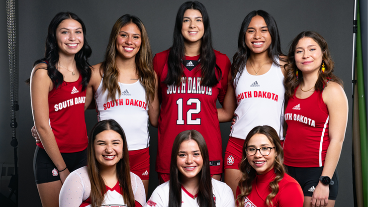 USD's eight female Native student-athletes stand together for a photo, each wearing their sports jersey.