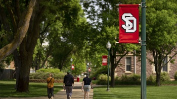 Three USD students walk together on the sidewalk's of USD's campus near Old Main. Three USD students walk together on the sidewalk's of USD's campus near Old Main.