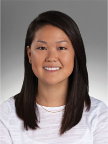 Sarah Shin posing for headshot in front of gray wall