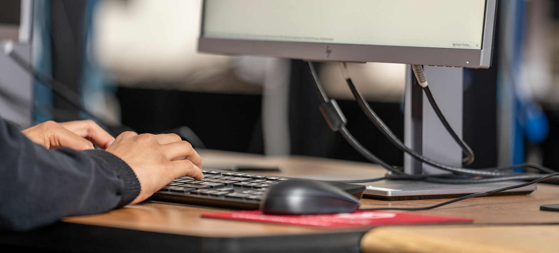 Desk with keyboard, monitor, mouse, and red USD mouse pad