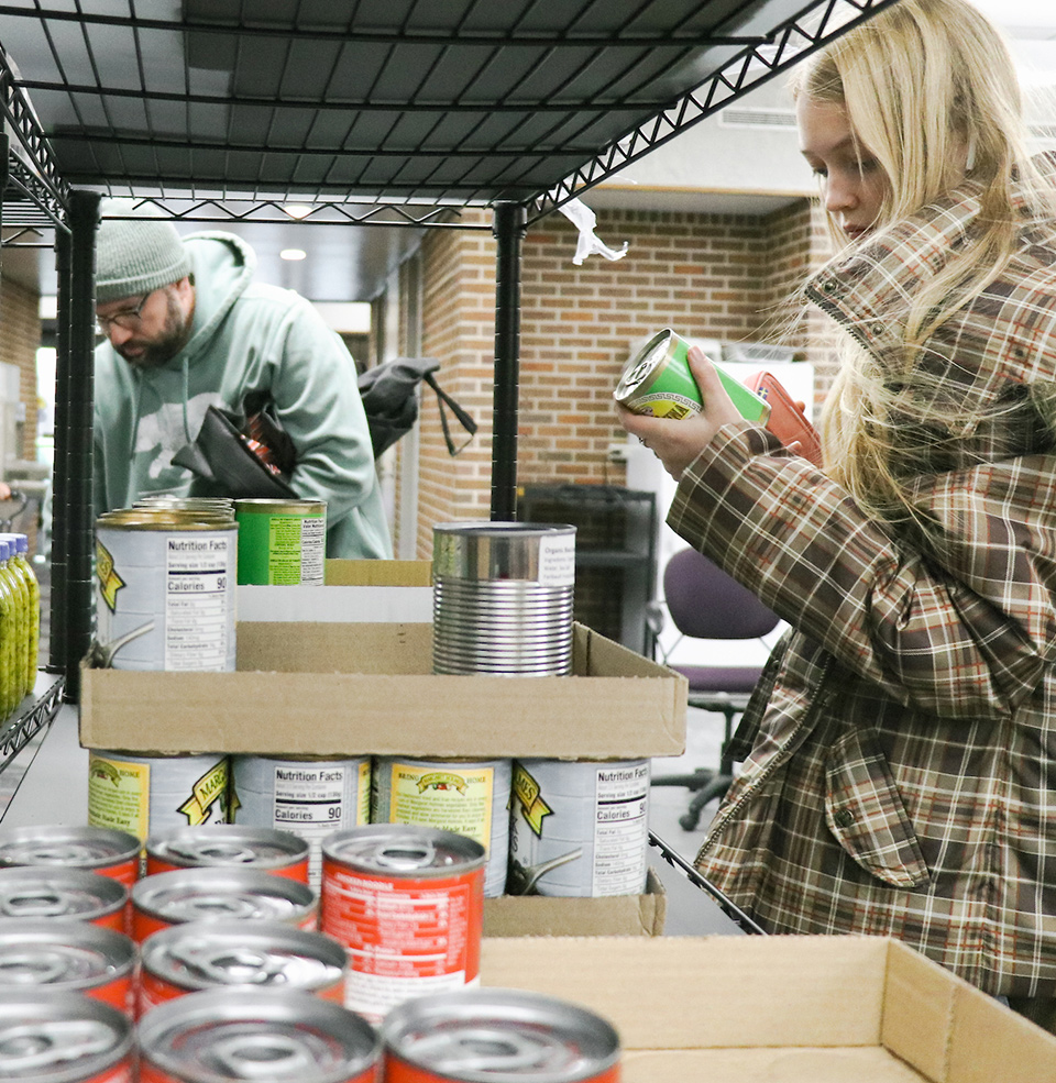 Students selecting canned food items at Charlie's Cupboard food panty.