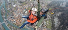 Two students taking a selfie video while skydiving over a town.