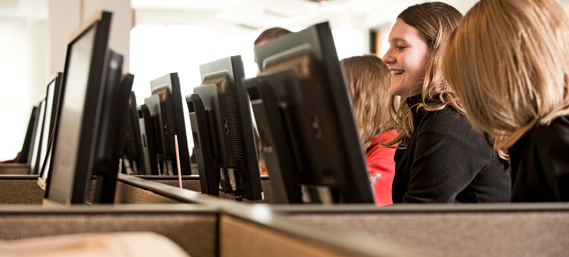 Several students smiling while working at computers