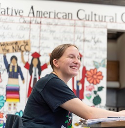 A student smiling and doing homework in the Native American Cultural Center.