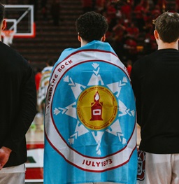 A native student wearing their tribal flag at a basketball game.