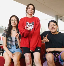 Three students sitting and smiling on the Native American Cultural Center couch.