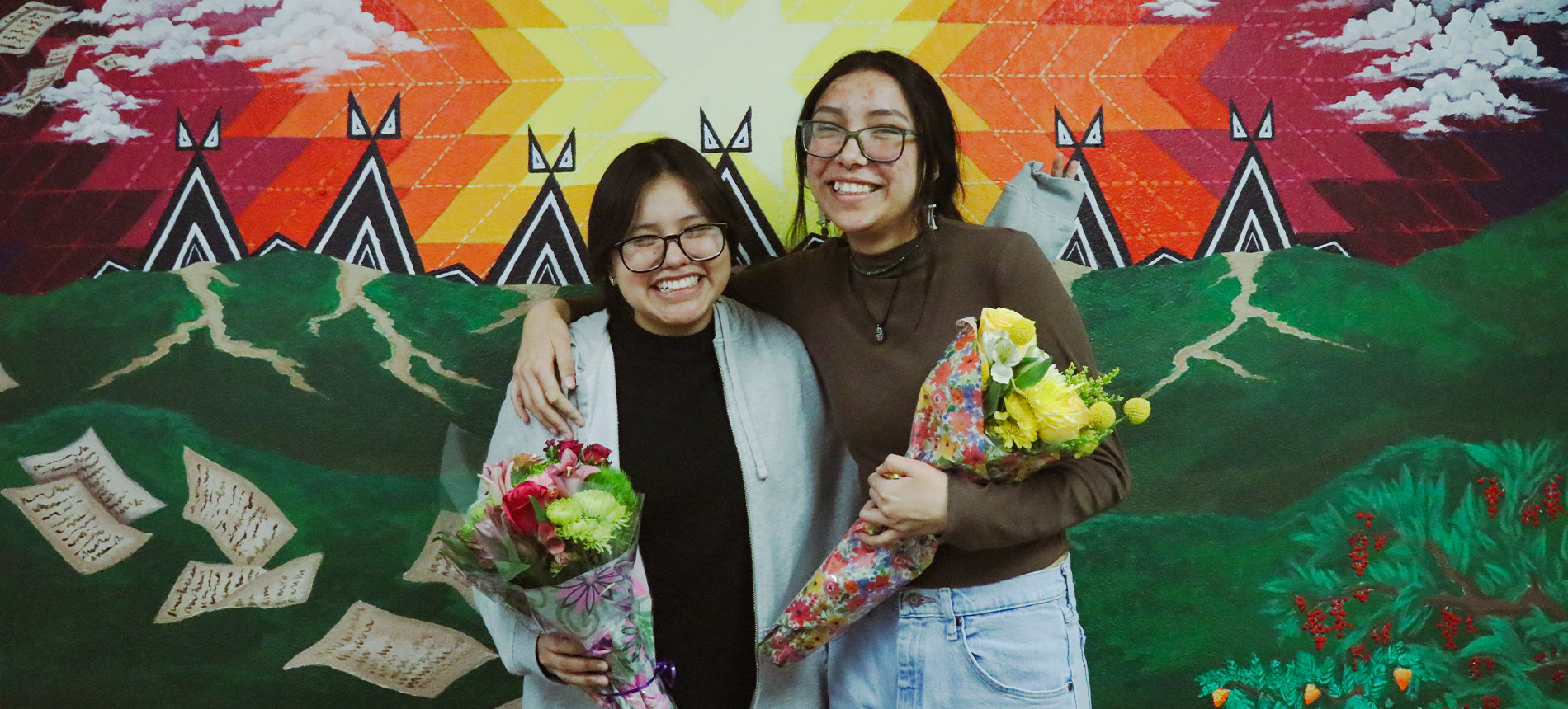 Students posing in front of a wall mural