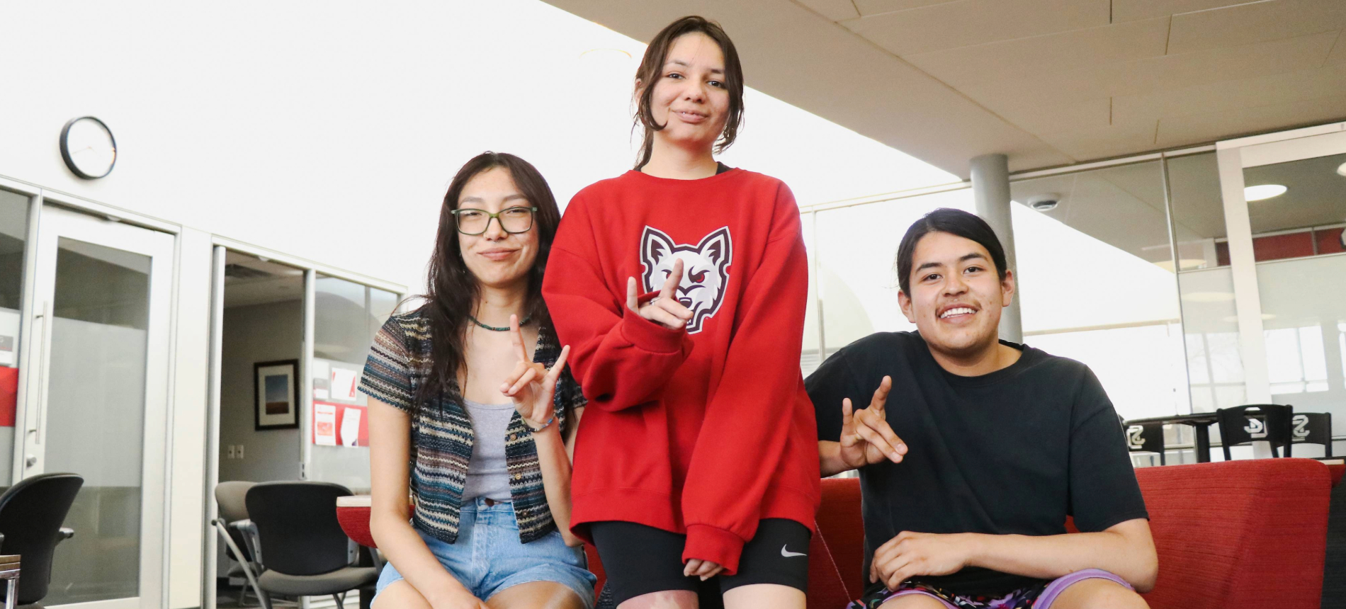 Three students sitting and smiling on the Native American Cultural Center couch.