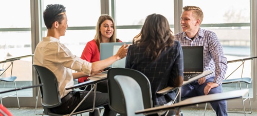 Four Students Sitting Around a Table Talking.