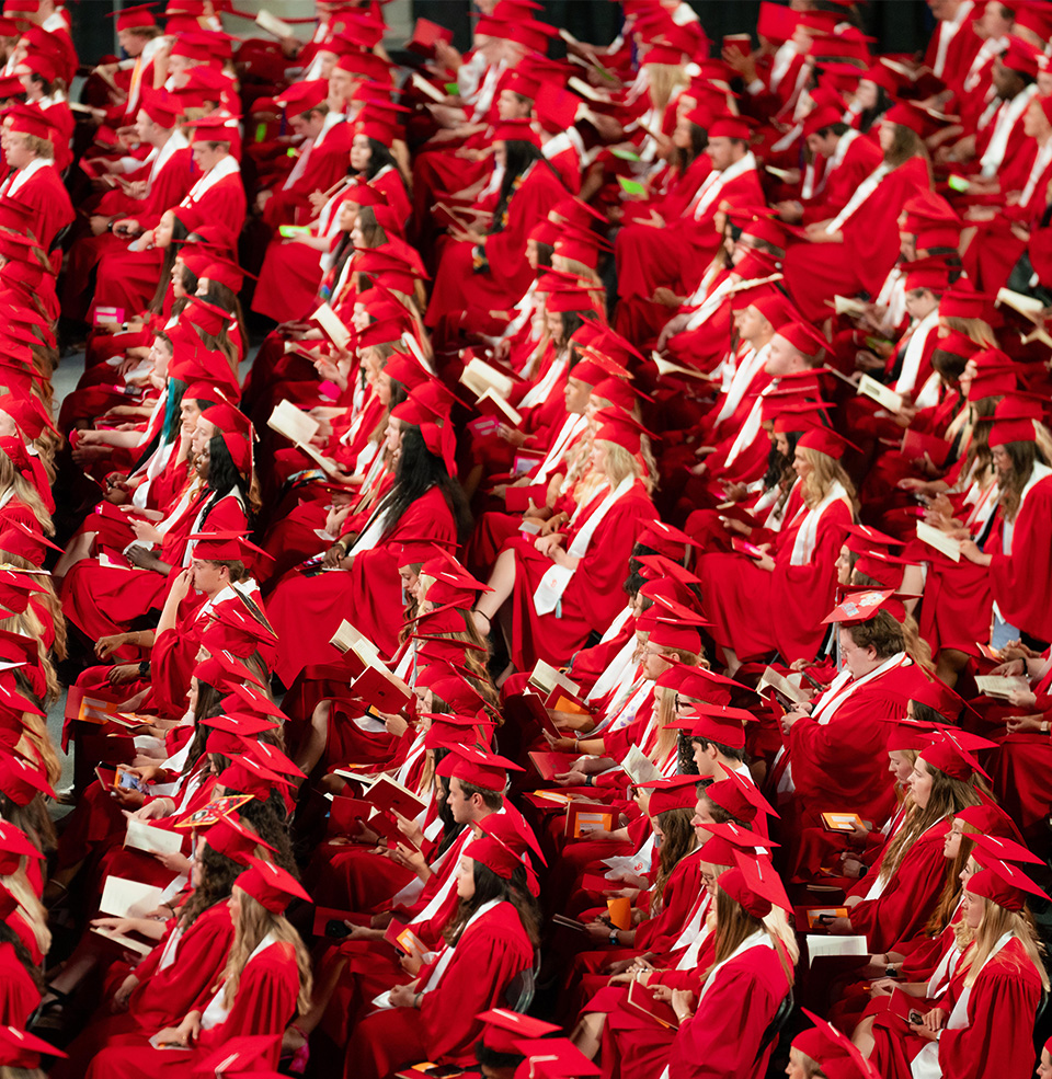 Photo of students sitting in rows in their cap and gown.