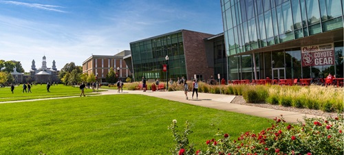 Spring shot of campus outside of the Muenster University Center with students walking on the sidewalks