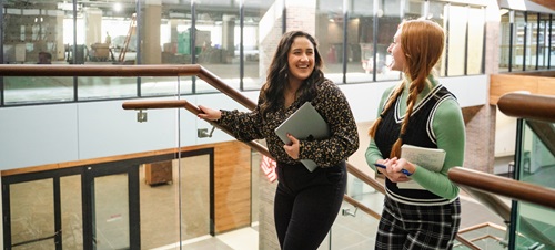 2 students smiling and walking up the stairs of the Sioux Falls main campus.