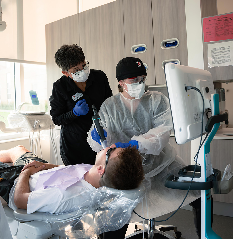 Student and teacher working in the dental section of the health and sciences building.
