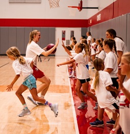 A young girl's basketball camp with a USD basketball player leading the event.