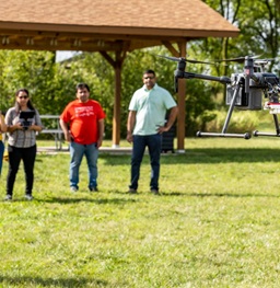 Students and teacher flying a drone outside