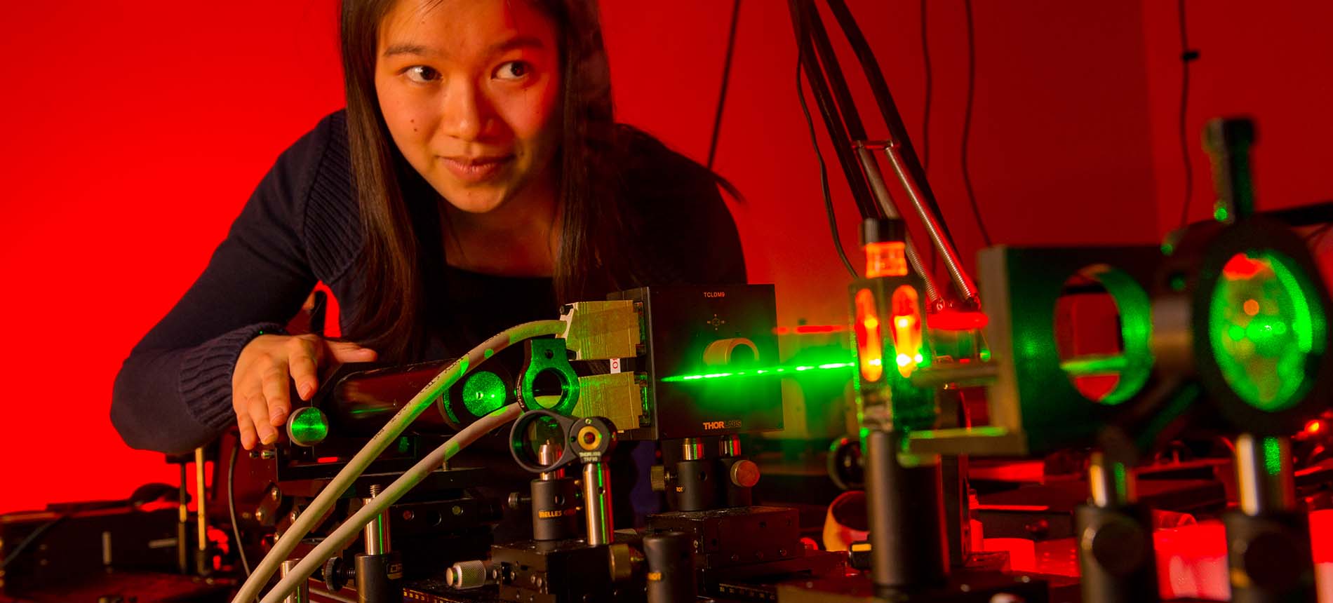 Student in science lab watching green laser.