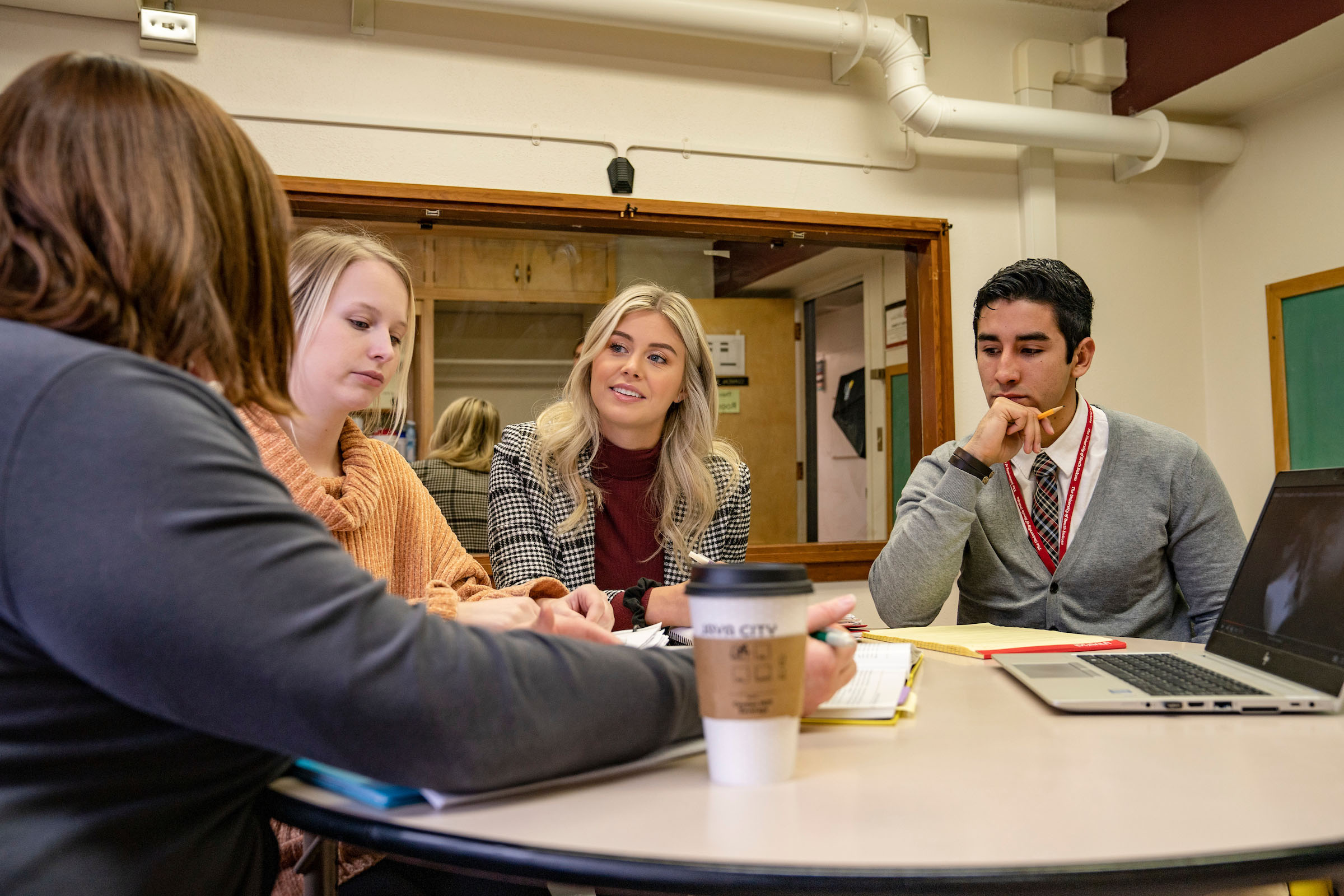 Several students sitting and a table and discussing