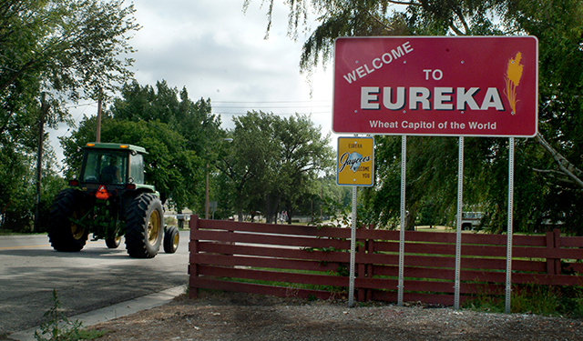 Photo of a sign of Eureka with a tractor driving on the road in the background