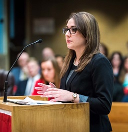 Law School student presenting into microphone at lectern.