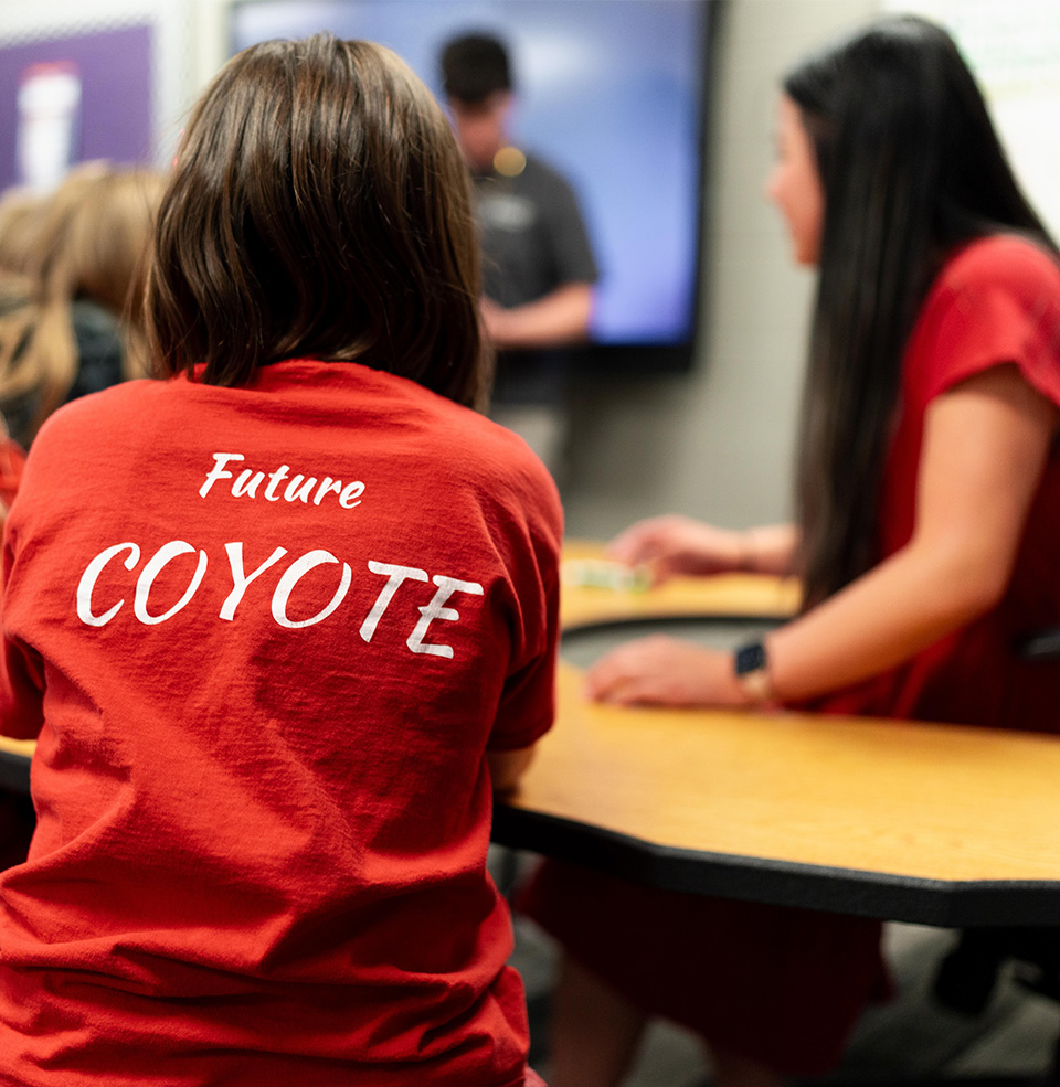 Child in classroom with background that says future coyote.