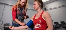 Student with Stethoscope Taking Another Students Blood Pressure.