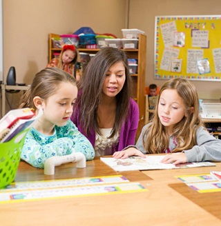A teacher instructing two children.