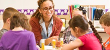 Teacher Sitting at a Table with Students.