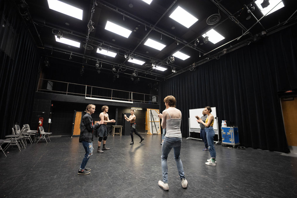 Students practicing in a large room painted black