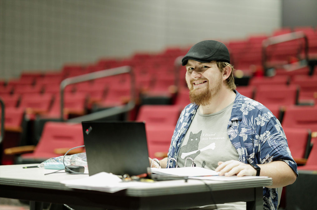 Technical production director smiling at a desk with a computer