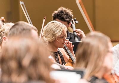 Students playing string instruments at concert