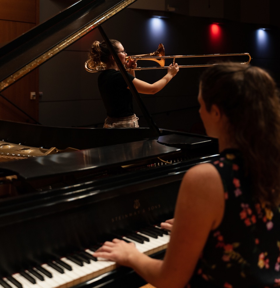 A USD student playing piano on stage, accompanying a trumpeter.