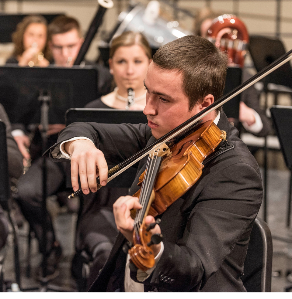 The USD Symphonic Orchestra playing on stage with all instruments.