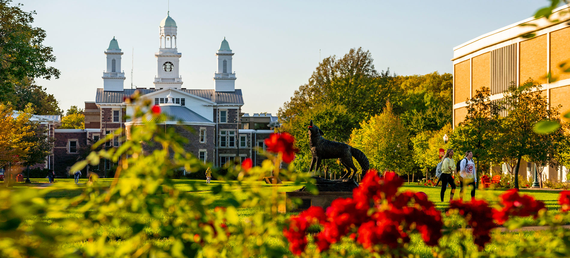 Rear view of the historic building, Old Main with the Legacy coyote sculpture in the foreground.