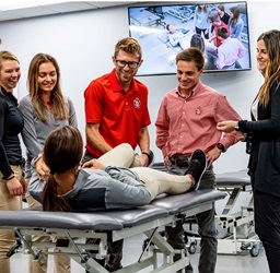 A group standing around a patient who is lying on a table or bed