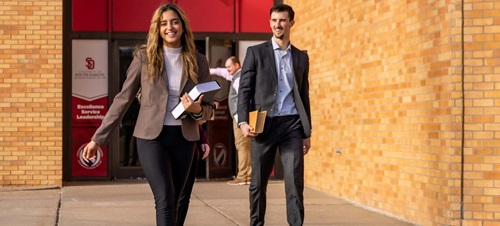 Law Students Holding Books While Walking Out of Building.
