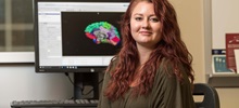 Female Sitting in Front of a Computer with a Brain Diagram on the Screen