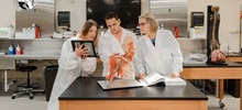 Three medicine students looking at a tablet working in the Human Anatomy laboratory.