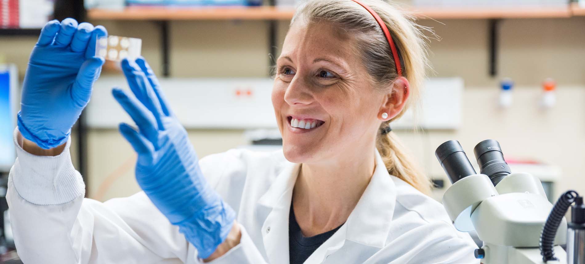 Female in White Lab Coat Examining a Medical Slide.