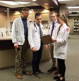 A group of Medicine students looking at a clipboard together.