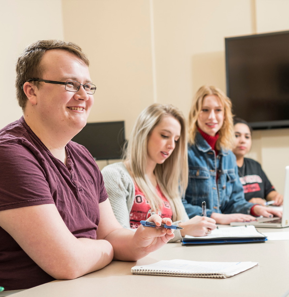 Several Communications students sitting at a conference table working together