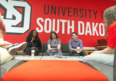 Three English students smiling having a meeting.