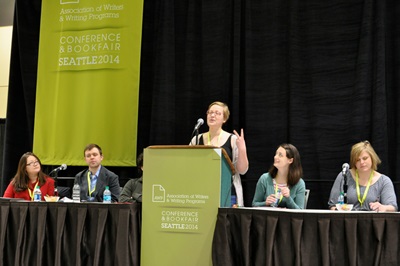 A speaker at a conference with panelists.