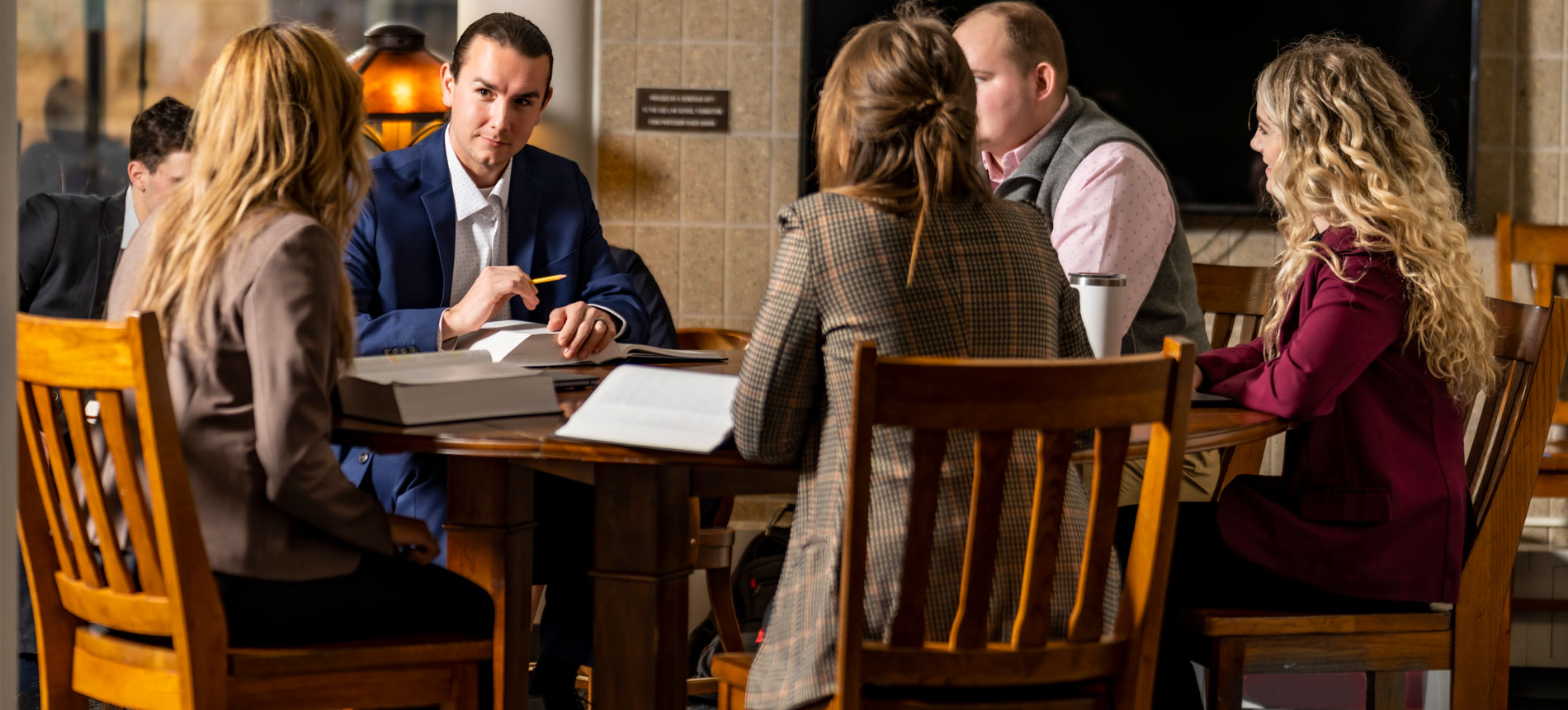 group of students sitting around a wooden table meeting