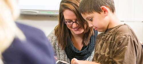 A teacher helping a child read.