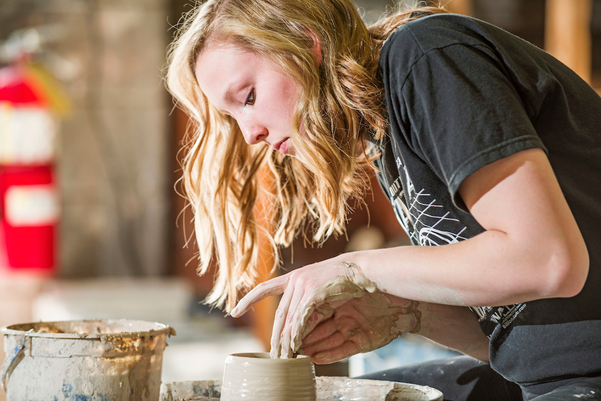 A student throwing a clay pot or jar 