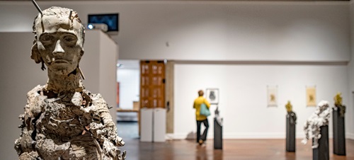 Art gallery with a sculpture prominently displayed. The sculpture is of a human's face but looks ragged and hard.