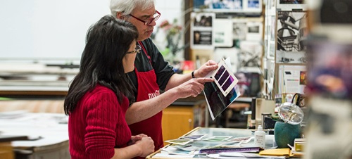 Student reviews black and white photo prints and negatives in photo lab