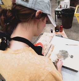Student works on lithography project in printmaking studio