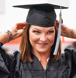 A student in their cap and gown smiling.