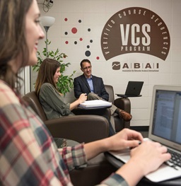 A student typing on her laptop in an office.